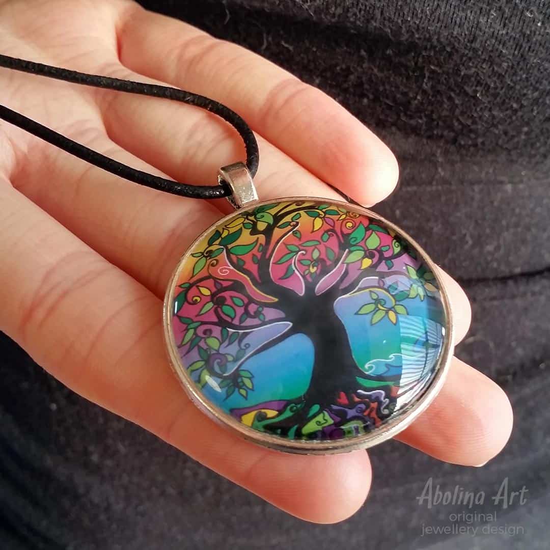 Tree of Life Psychedelic Dawn pendant held in model's hand