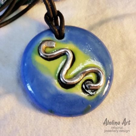 Silver Snake symbol pendant on blue and yellow background