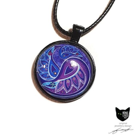 Art pendant with paisley inspired artwork in purple violet hues in black bezel, with glass cabochon sealing the artwork