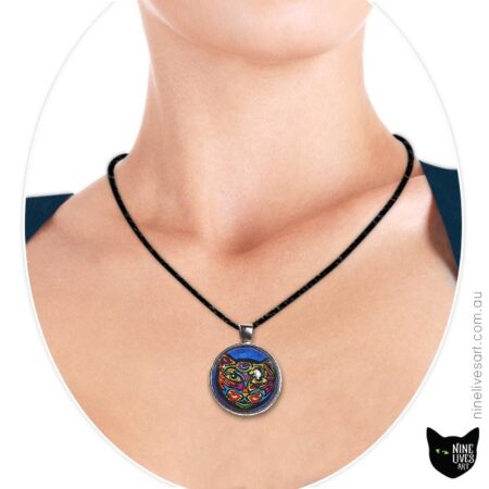 Bold colourful cat on blue background sealed under glass cabochon and strung on cord