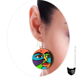 Model wearing hand-painted earrings depicting colourful faces