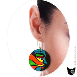 Model wearing hand-painted earrings depicting colourful faces
