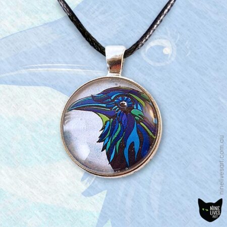 25mm cabochon pendant featuring blue raven on pale sky background, strung on black cord