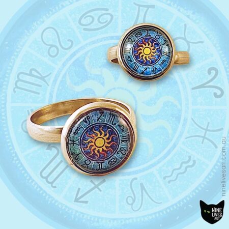 Zodiac Sun rings 12mm cabochon setting displayed on backdrop featuring original artwork