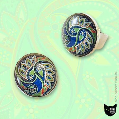 25mm handmade rings with paisley design sealed with glass cabochons on faint green background
