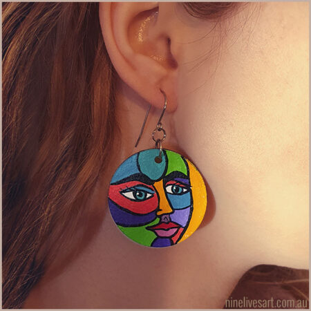 Model wearing hand-painted earring with bold face design