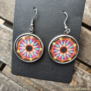 Sun Mandala earrings in purple colours, hung on black jewellery card